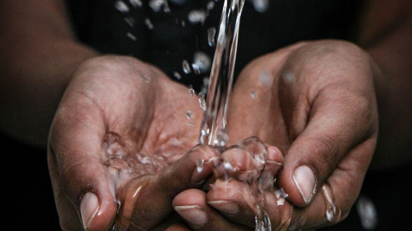 Clean, clear water pouring into a pair of cupped hands